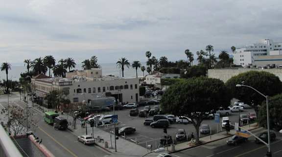 A city street with cars and palm trees.