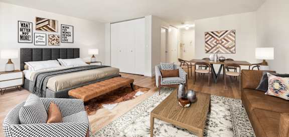 A modern bedroom with a large bed and a dining area in the background at The Ellington Apartments, New York, NY, 10019