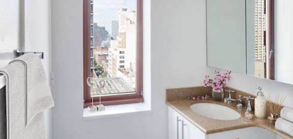 A bathroom with a large window overlooking a cityscape at The Ellington Apartments, New York, NY, 10019