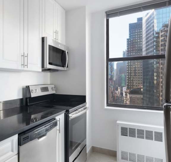 A modern kitchen with black countertops and white cabinets.