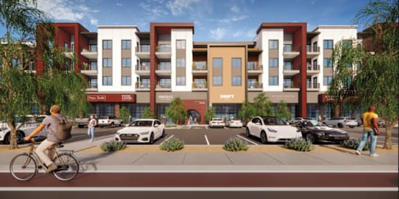 A modern apartment complex with a parking lot in front.