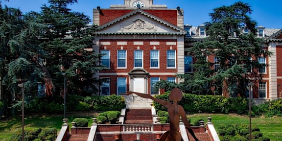 A large red brick building with a statue in front of it