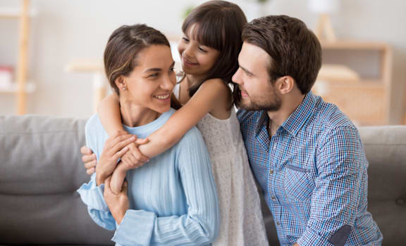a man and woman sitting on a couch with their daughter