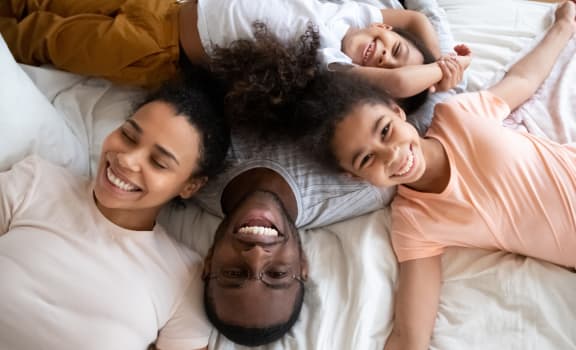 a family lying on a bed with a smile on their face
