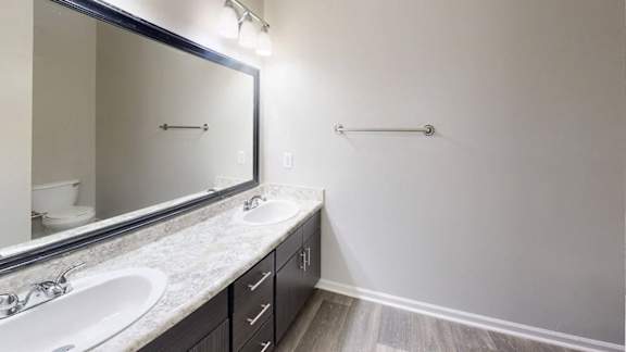 A bathroom with a sink, mirror, and a towel bar.