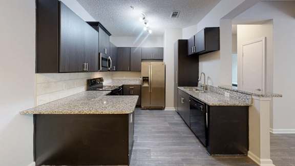 A kitchen with dark brown cabinets and granite countertops.