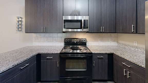 A kitchen with black cabinets and a granite countertop.