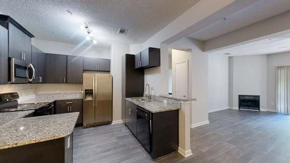 A modern kitchen with dark wood cabinets and a granite countertop.