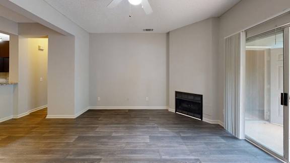 A spacious room with a fireplace and wood flooring.