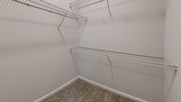Empty white room with a carpeted floor and wire shelving.