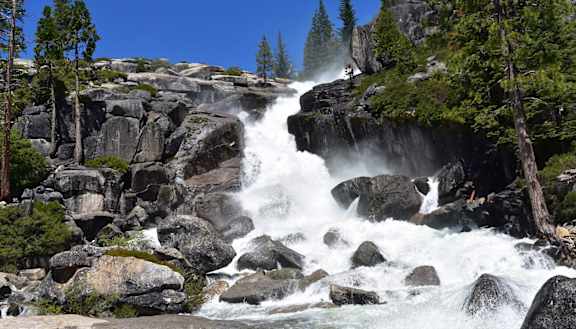 A waterfall cascades over a rocky cliff surrounded by trees.