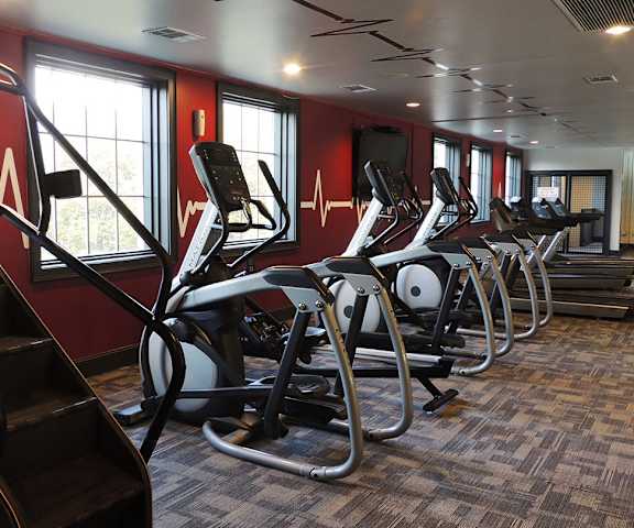 A gym with cardio machines, TVs, and weights at Firestone at West 7th Apartments. 