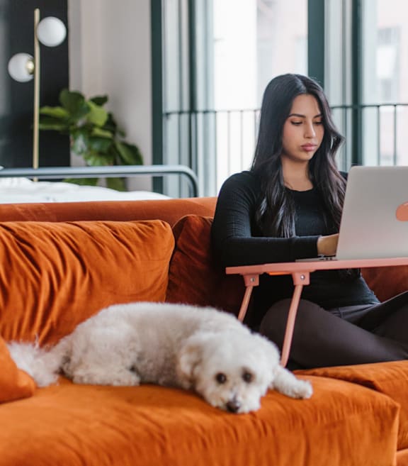 Woman sitting with her dog on an orange couch in a loft.