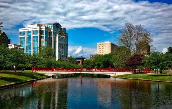 Distant buildings and a Japanese style bridge crossing over the water in Huntsville, AL's Big Spring Park