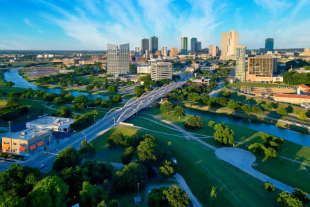 a river flows through a park with a city in the background
