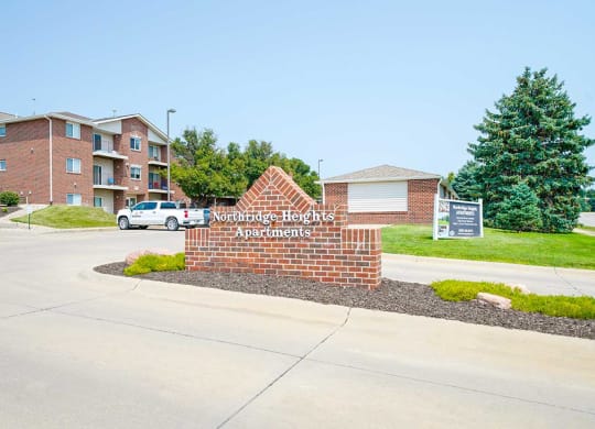 Brick monument entrance sign with landscaped greenery around it