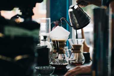 A person is pouring a dark liquid into a glass.