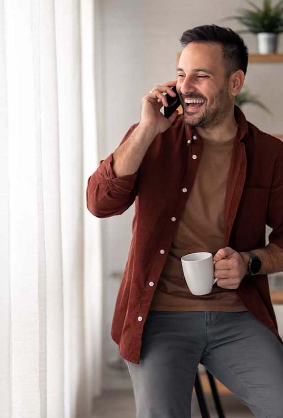 a man talking on a cell phone while holding a coffee cup