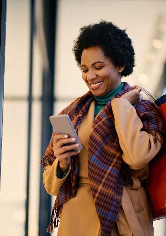 a woman looking at her cell phone while standing in a store