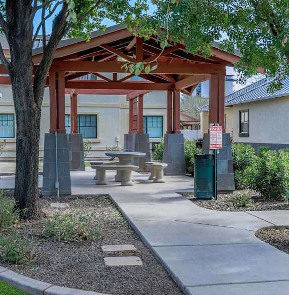 A covered outdoor seating area with a table and chairs.