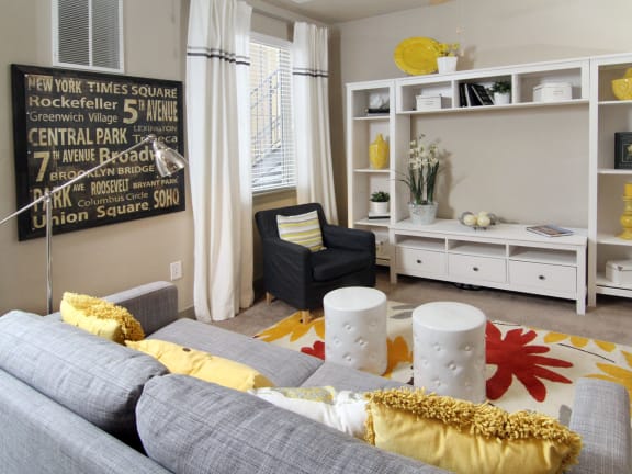 a living room with a gray couch and yellow and white pillows
