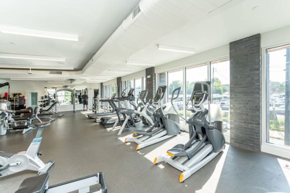 a gym with cardio equipment and windows in a building
