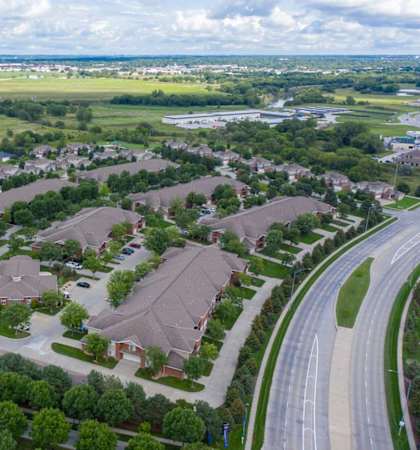 an aerial view of apartment community with multiple buildings, houses and cars