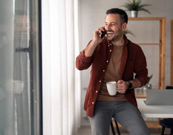 a man talking on a cell phone while holding a coffee cup