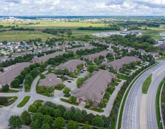 an aerial view of apartment community with multiple buildings, houses and cars