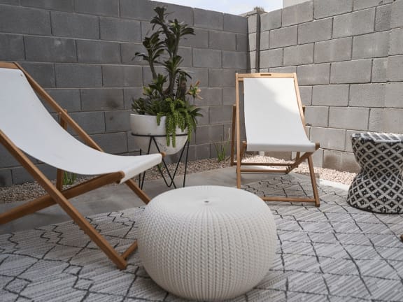 a patio with two chairs and a white ottoman and a mirror and plants at Novella Biltmore, Phoenix, AZ 85016