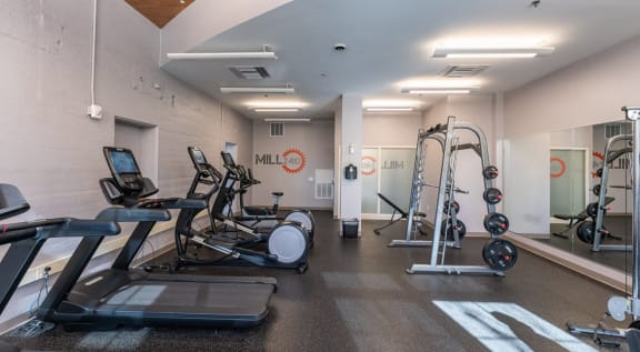 a gym with cardio equipment and weights on the floor