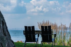 a pair of black lawn chairs sit in front of a wooden table with a view of the