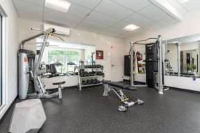 a gym with weights and cardio equipment and a window