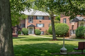 a brick building with a lawn and trees in front of it