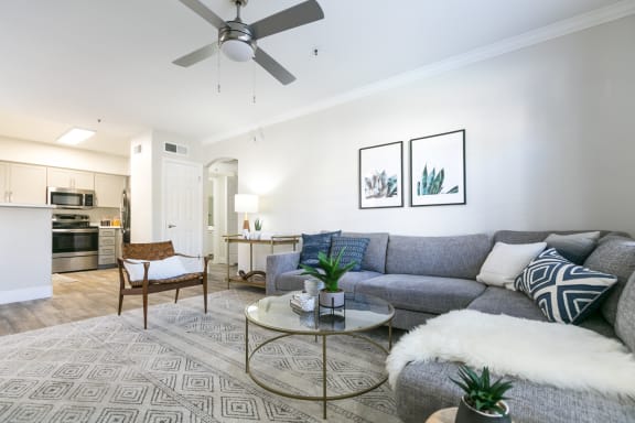 a living room with a couch coffee table and chair and a kitchen in the background