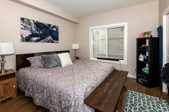A bedroom with a bed, nightstand, and a painting on the wall.