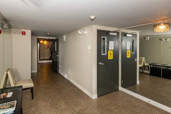 A hallway with a black door on the right and a white door on the left.