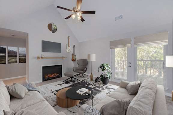 A living room with a fireplace, a couch, a chair, a coffee table, and a ceiling fan.