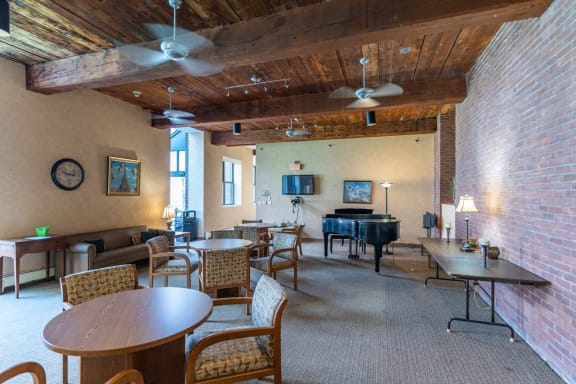 a living room with a piano and tables and chairs