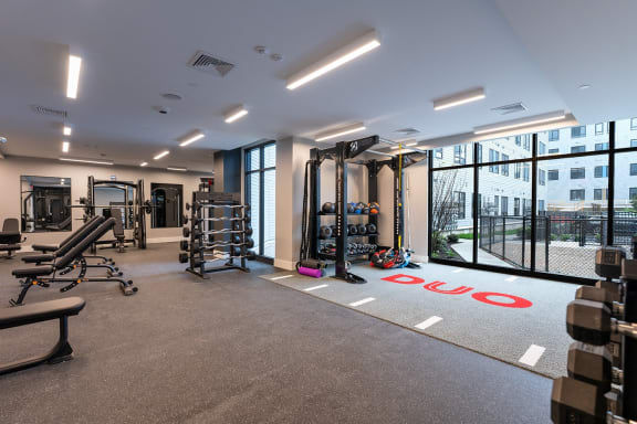 a gym with weights and cardio equipment in a building with large windows