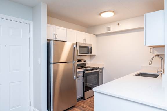 A kitchen with a refrigerator, microwave, oven, and sink.