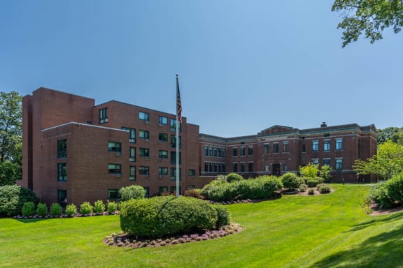 a large brick building with a flagpole and a green lawn