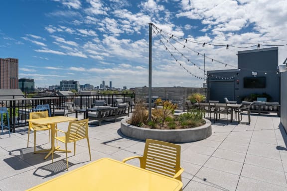 a rooftop patio with tables and chairs and a fire pit at Union 346, Somerville, MA