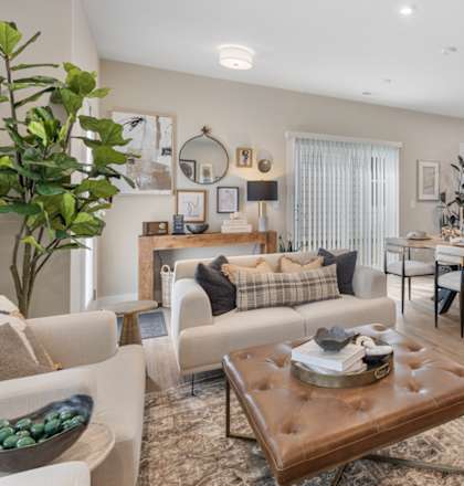 Open-concept living room in single-family rental home at Mural Lewis Center featuring wood-style flooring, neutral tones, modern furnishings, large windows, and seamless connection to dining area