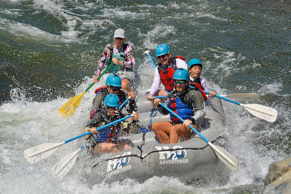 A group of people are white water rafting on a river.