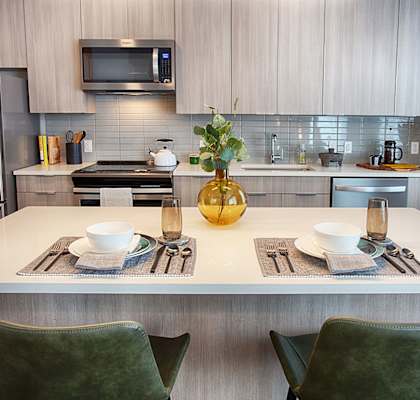 A modern kitchen with a white table and green chairs.