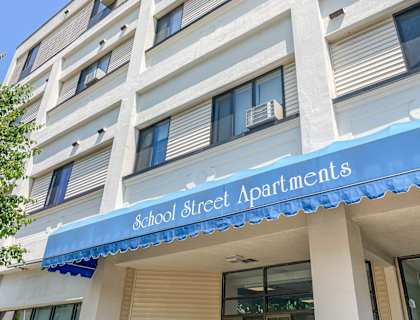 A building with a blue awning that says School Street Apartments.
