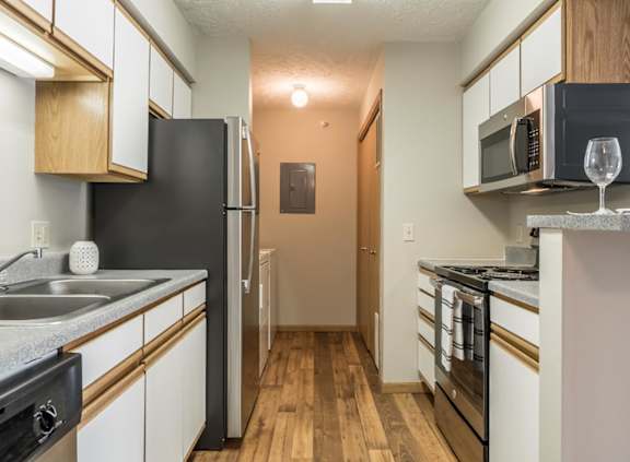 A kitchen with stainless steel appliances and white and oak cabinets.
