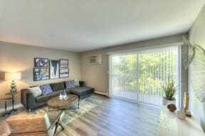 spacious living room with wood plank flooring and a sliding glass door 