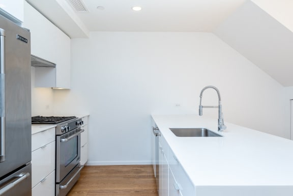 a white kitchen with stainless steel appliances and a white counter top